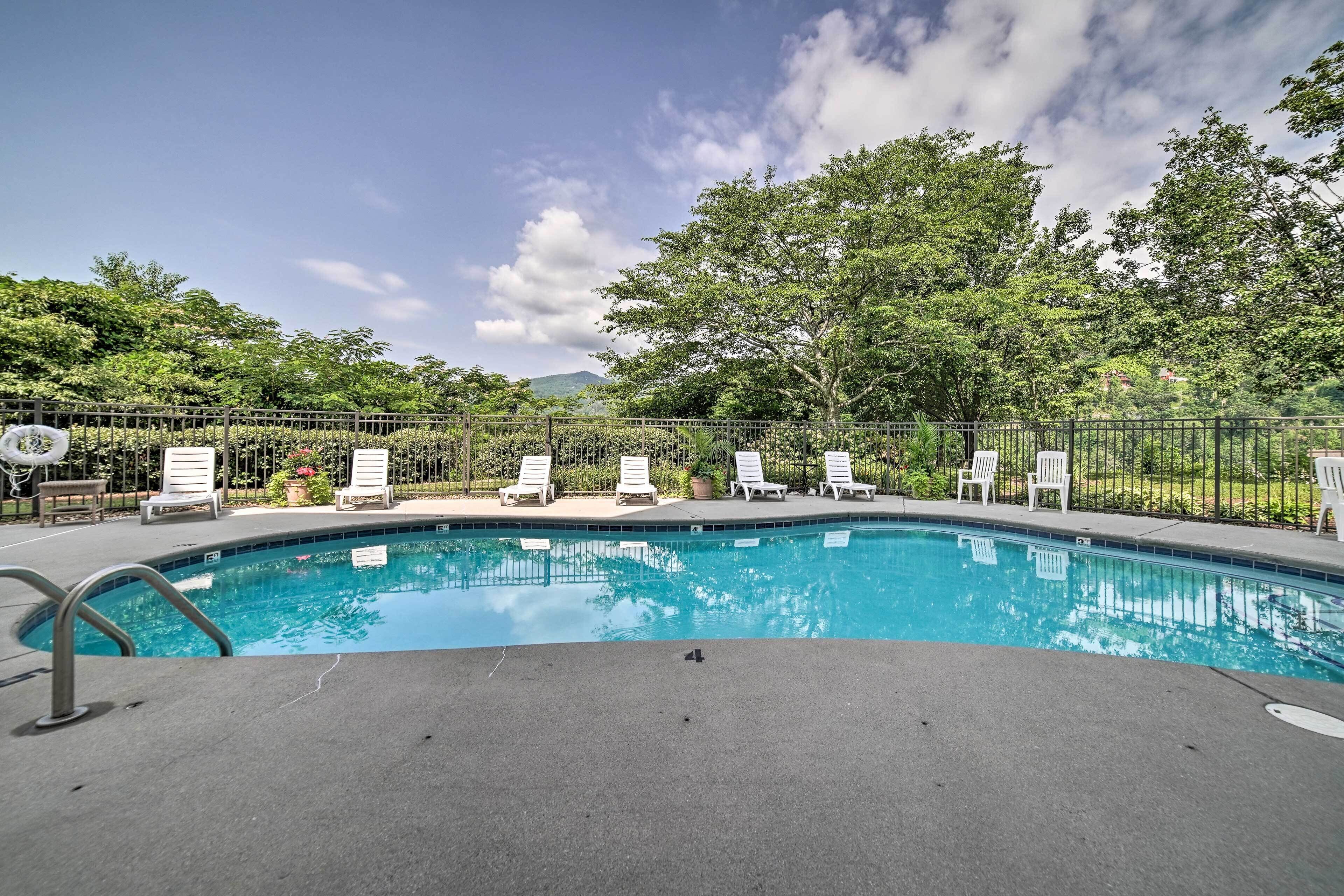 A swimming pool with lounge chairs and a fence.
