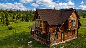 A log cabin with a sloped roof, a porch, and a view of a mountainous landscape. - Mountain Cabin Rental Near Steamboat Springs, Colorado with Mountain Views (Clark)