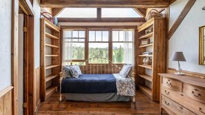 Une chambre confortable avec un lit, des étagères en bois et une vue sur l’extérieur.
