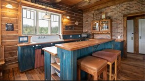 Une cuisine rustique avec un bar en bois, une grande fenêtre et un mur en briques.