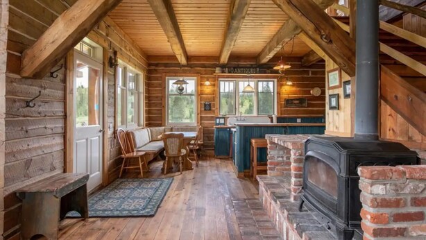 L’intérieur d’une cabane en rondins comprend un coin repas, une cheminée et une enseigne sur laquelle on peut lire « ANTIQUITÉS ».