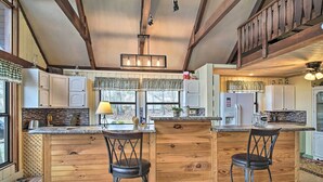 A kitchen with wooden cabinetry, a central island with stools, and a hanging light fixture. - Douglas Lake Cabin w/ Mountain-view Deck & Grill (White Pine)