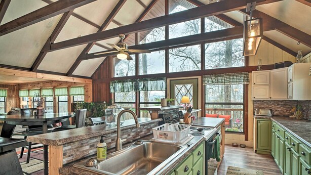 A spacious kitchen with a large island, wooden cabinets, and a view through the windows. - Douglas Lake Cabin w/ Mountain-view Deck & Grill (White Pine)