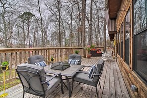 A wooden deck with outdoor furniture, including a table and chairs, surrounded by a wooden fence and trees. - Douglas Lake Cabin w/ Mountain-view Deck & Grill (White Pine)