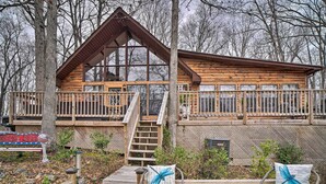 A wooden cabin with a balcony, a staircase, and two chairs with blue cushions. - Douglas Lake Cabin w/ Mountain-view Deck & Grill (White Pine)