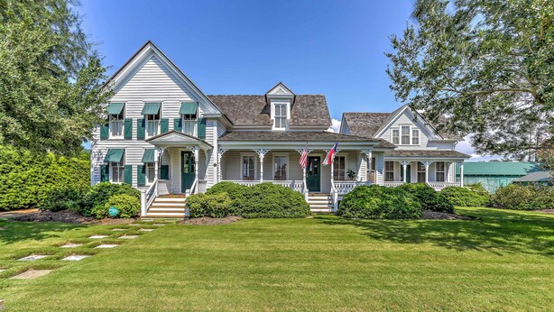 A large, two-story house with a front porch, a flag, and a well-maintained lawn. - Historic Manteo House on Roanoke Sound w/ Dock! (Manteo)