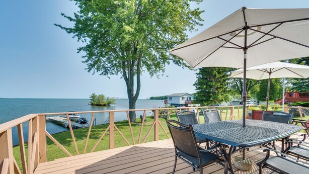 A wooden deck with a table and chairs, overlooking a lake with a boat docked nearby. - Bayfront Red Creek Vacation Rental w/ Boat Dock! (Red Creek)