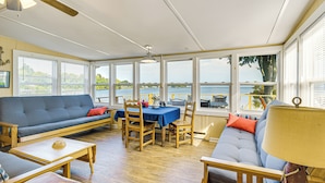 A sunroom with a view of the sea, furnished with a sofa, chairs, and a dining table. - Bayfront Red Creek Vacation Rental w/ Boat Dock! (Red Creek)