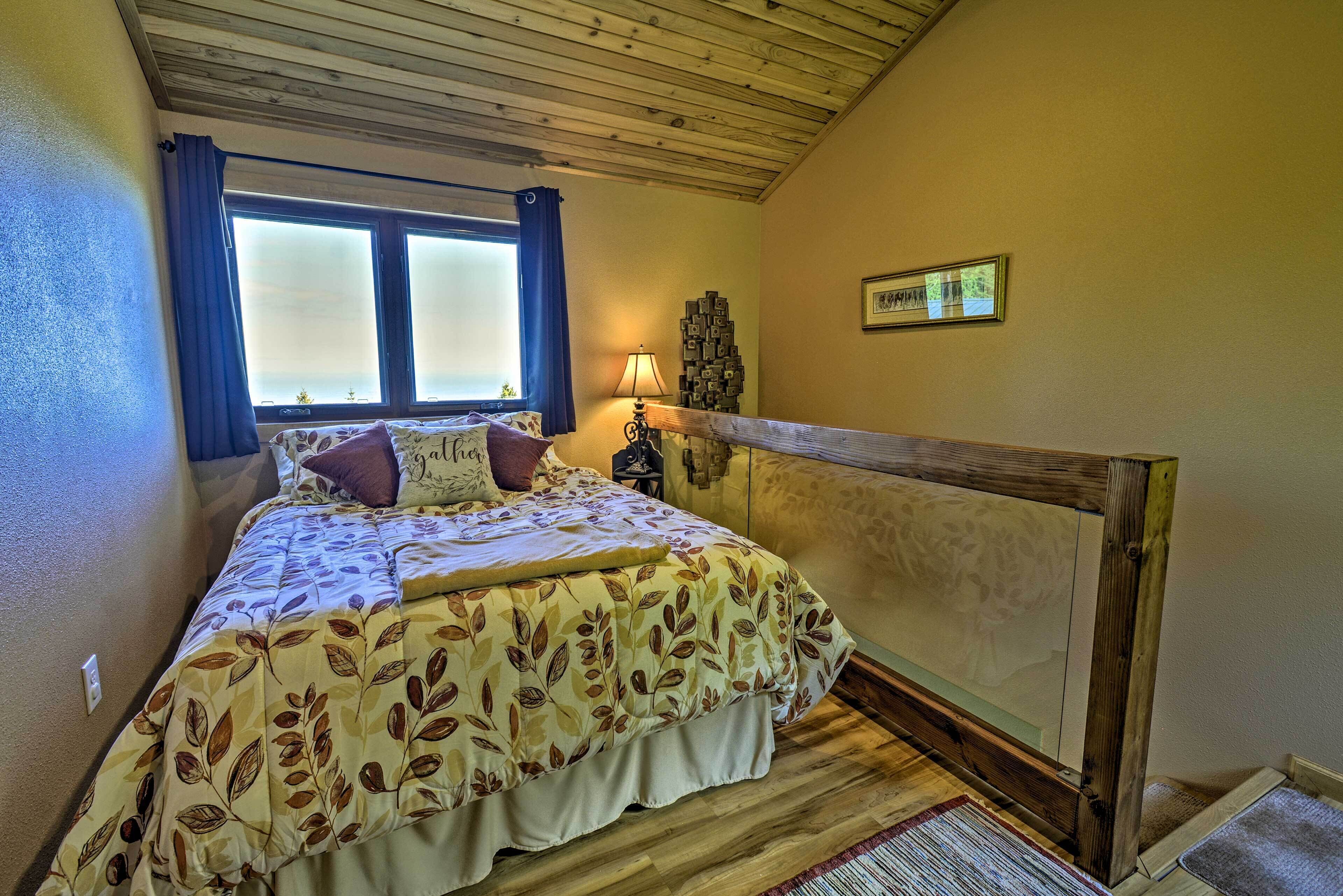 Un dormitorio con cama, ventana con cortinas, lámpara de noche y cabecera de madera.