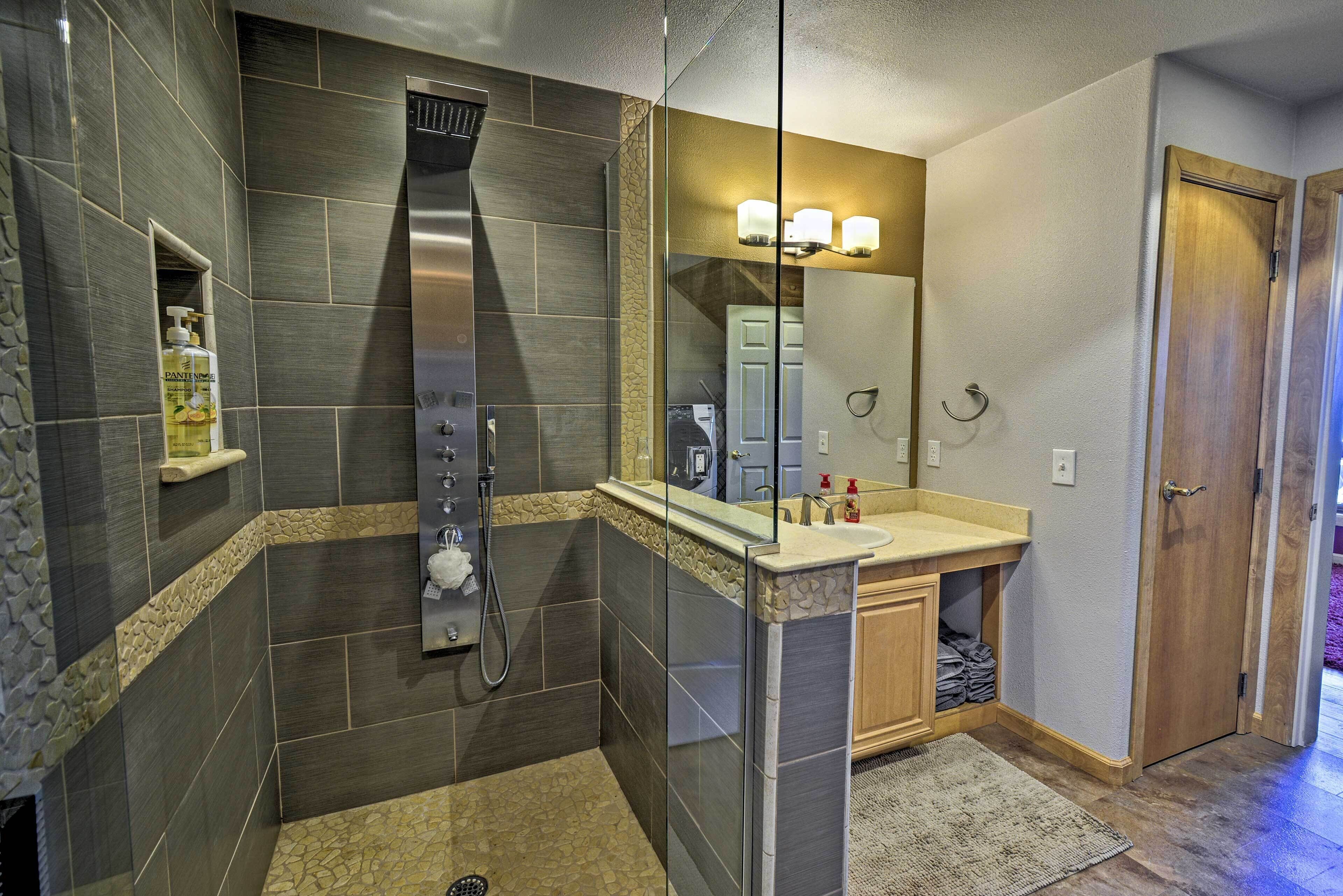 A modern bathroom with a glass-enclosed shower, a vanity with a mirror, and a wooden door.