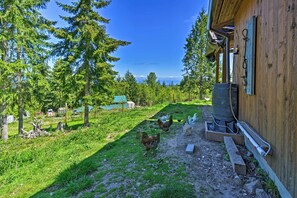 A rustic wooden building with a water tank and a chicken coop in a lush, green outdoor setting. - Picturesque Port Angeles Cabin w/ Fire Pit! (Port Angeles)