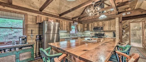 Una cocina rústica con vigas de madera, una isla grande y un refrigerador.