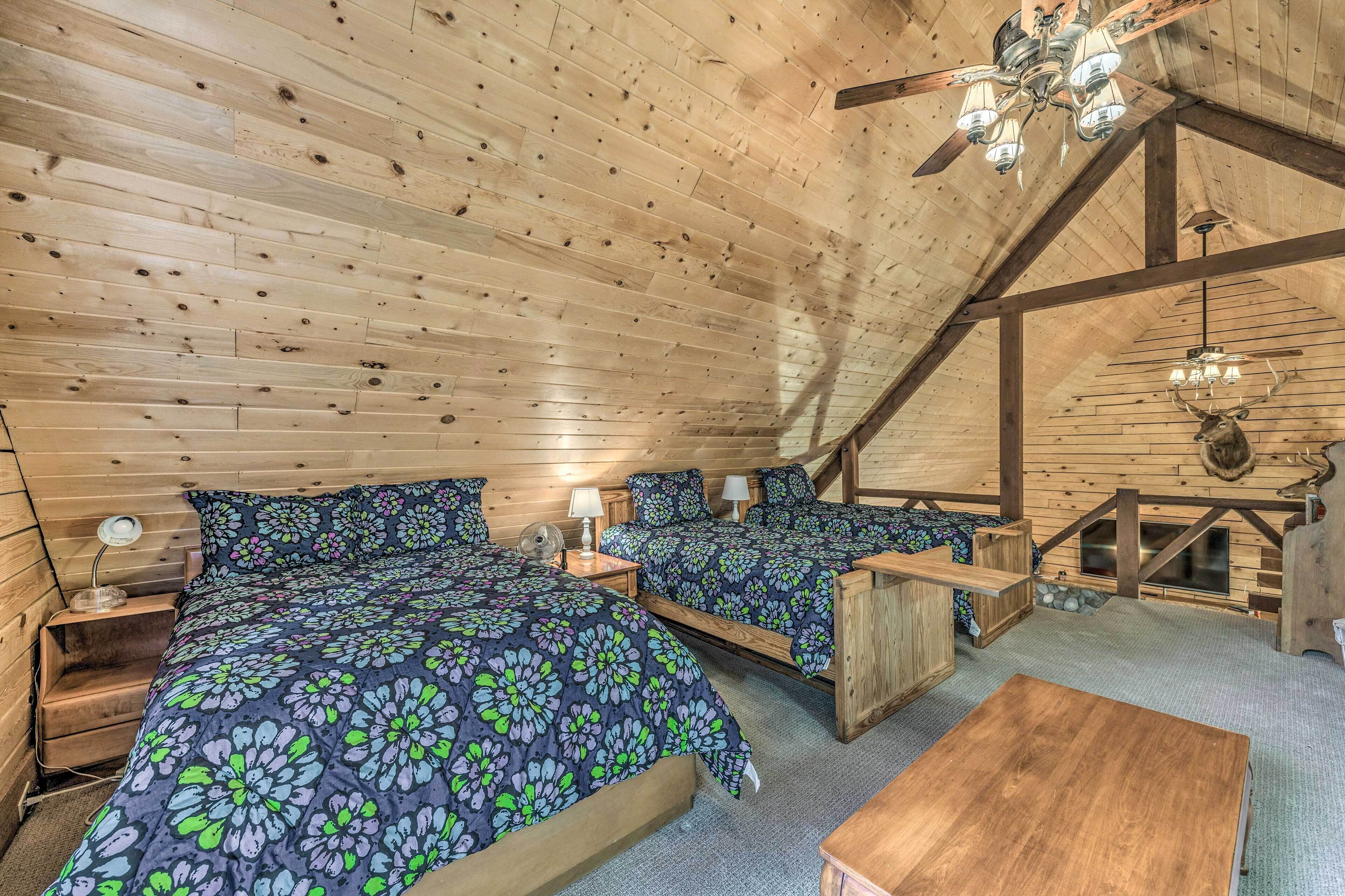 Une chambre confortable située sous les toits, avec deux lits, des poutres en bois et un lustre.