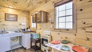 Cocina de cabaña de madera con pileta, estufa, alacenas y una mesa de comedor servida con platos y vasos.