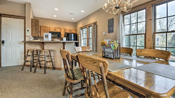 A spacious kitchen with wooden cabinets, a dining area with a large table and chairs, and large windows offering a view of the outdoors.