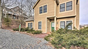 A two-story residential building with a beige exterior, multiple windows, and a green door.