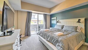 Un dormitorio con cama, escritorio, televisor y vista al exterior.