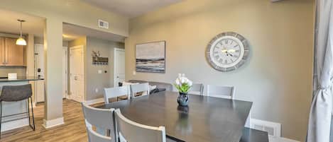 A dining area with a dark wooden table, white chairs, and a clock on the wall.