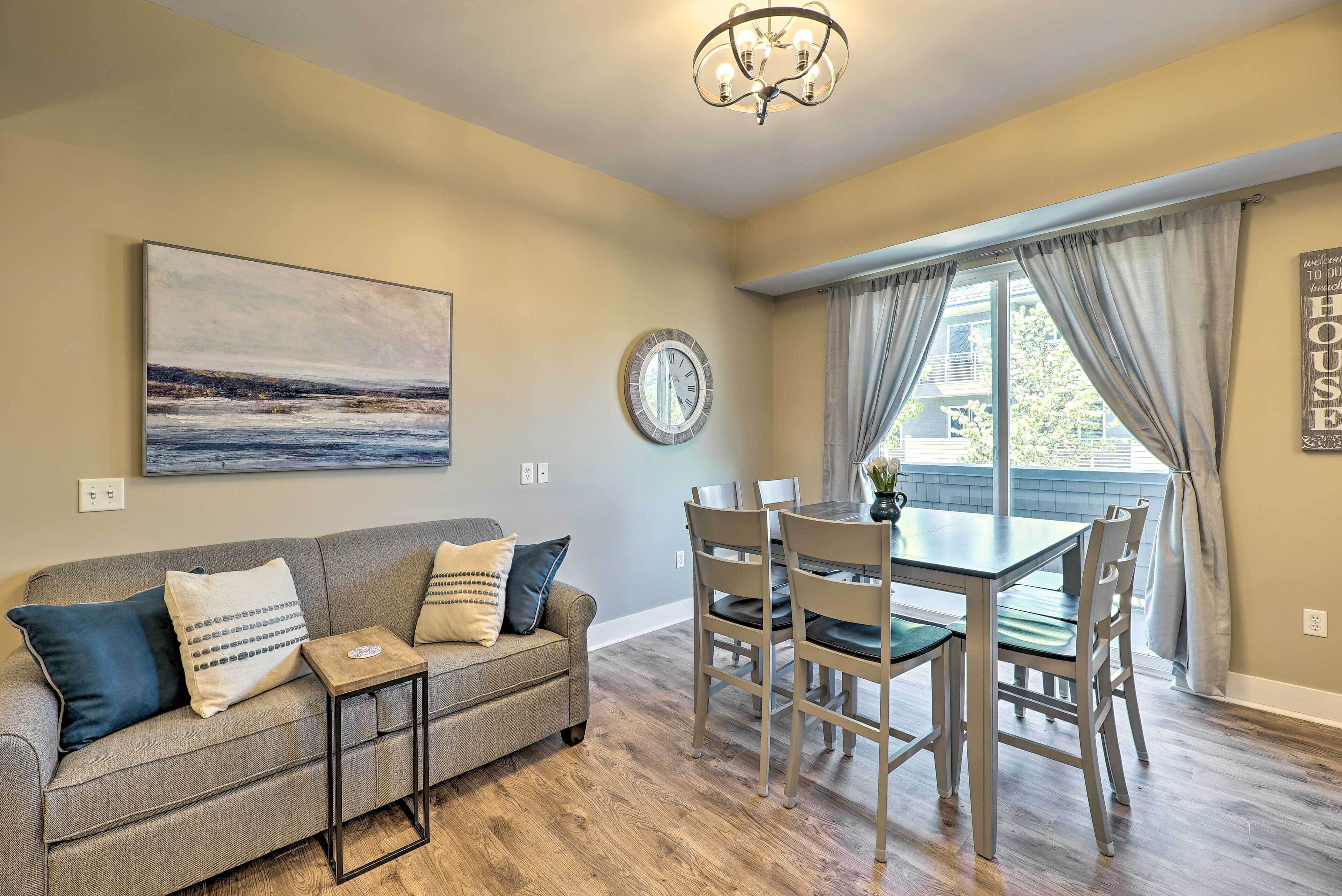 Un coin repas avec une table et des chaises, une horloge au mur et un tableau au-dessus du canapé.