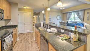 Una cocina moderna con encimeras de granito, electrodomésticos de acero inoxidable e iluminación colgante.