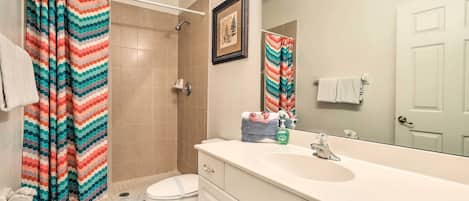 A bathroom with a shower, toilet, sink, and a mirror.