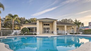 A swimming pool with a clear blue water surface, surrounded by a concrete deck.