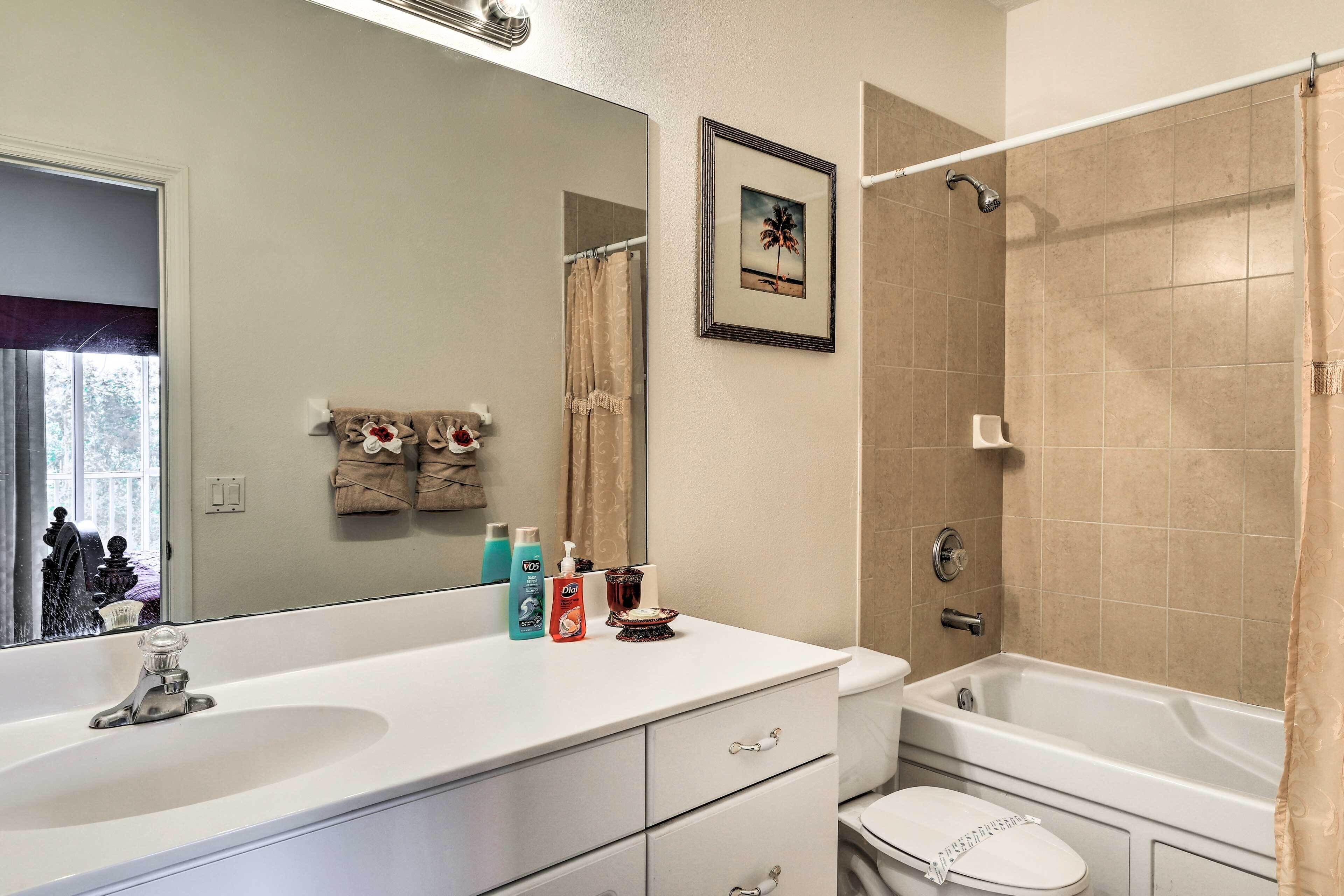 A bathroom with a white sink, a toilet, and a bathtub. There are toiletries on the sink counter.