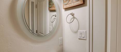 A bathroom with a round mirror, a bathtub, and a wooden sign with a bicycle.
