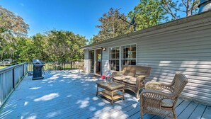 A covered deck with wicker furniture and a trash can.