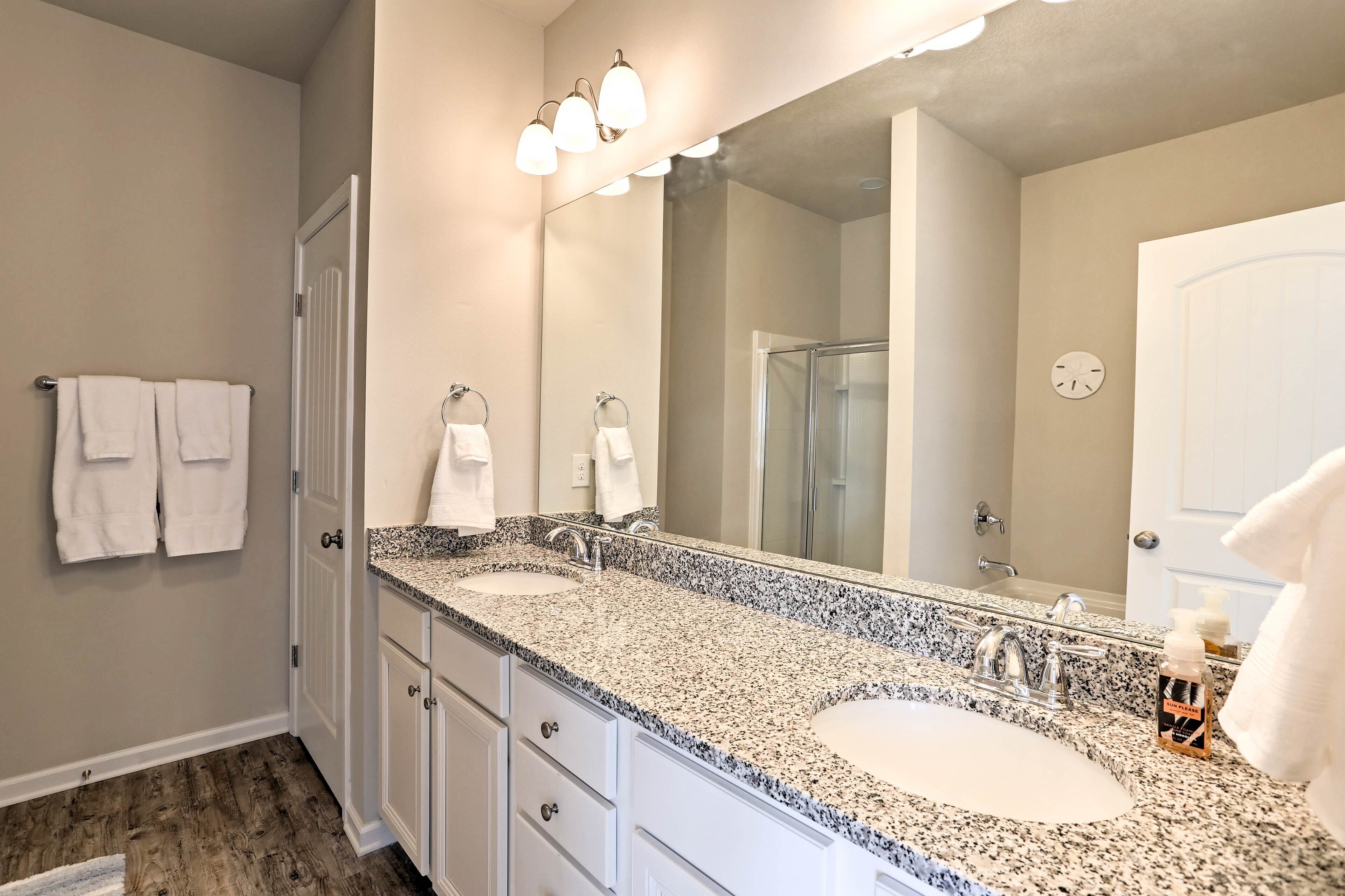 A bathroom with two sinks, a large mirror, and a shower.