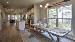 A spacious kitchen with a central island, large windows, and a dining area with a wooden table and benches. - Port St Joe Beach House w/ Pool Access! (Port St. Joe)