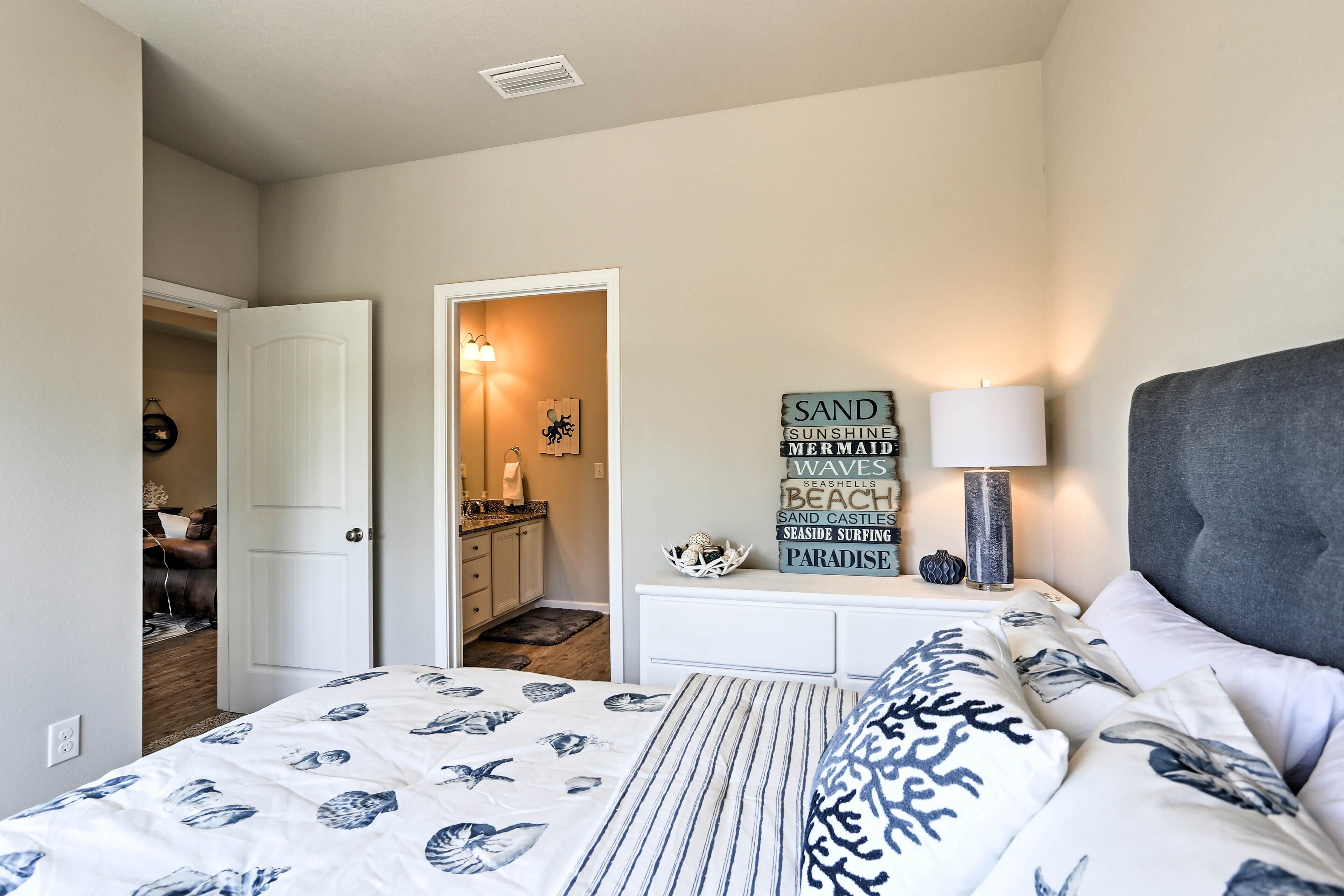A bedroom with a bed, a nightstand, a lamp, and a wall with decorative items.