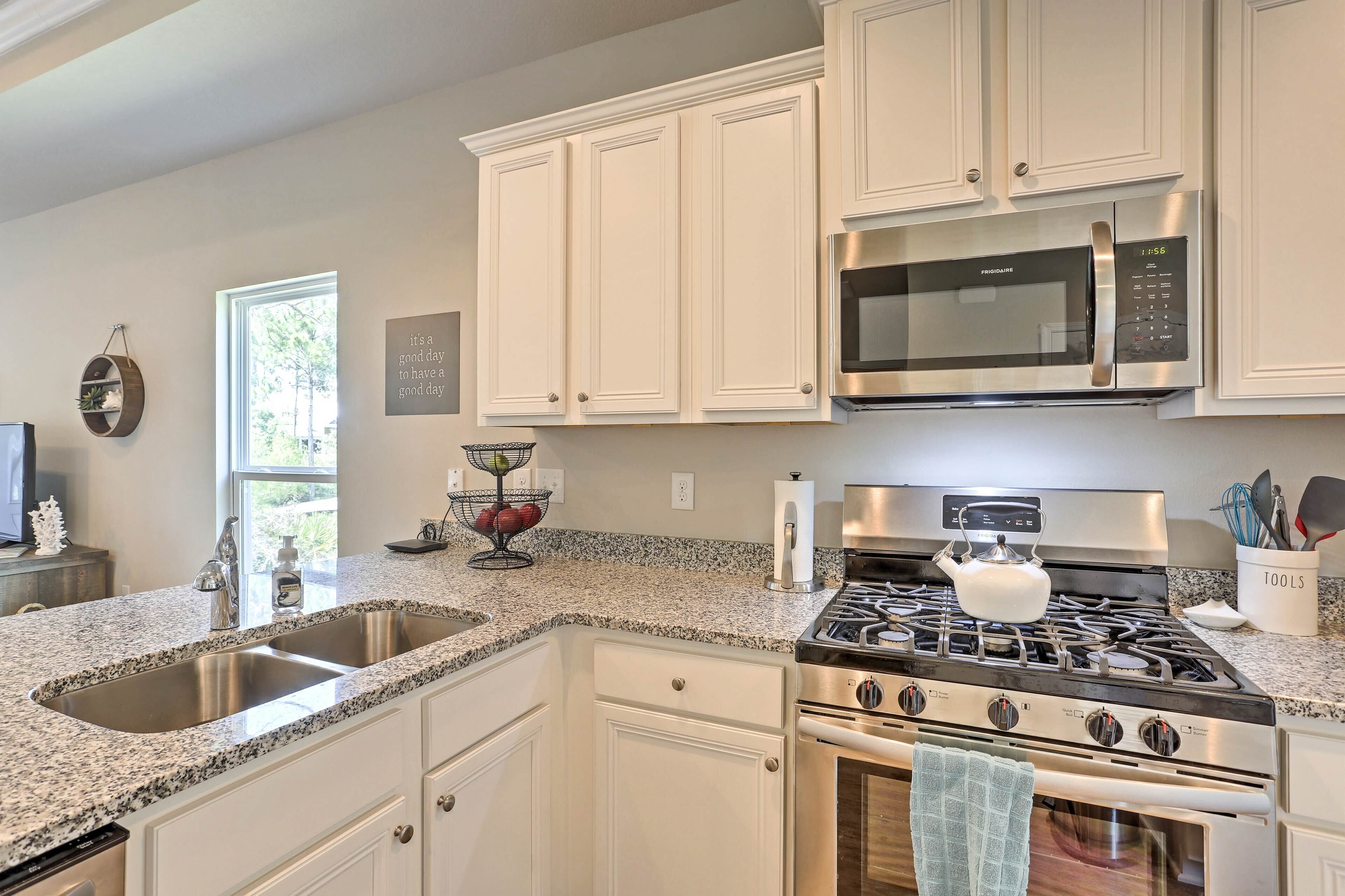 A kitchen with white cabinets, a stainless steel stove, a microwave, and a granite countertop.
