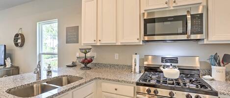 A kitchen with white cabinets, a stainless steel stove, a microwave, and a granite countertop.