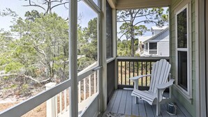 A covered porch with a white Adirondack chair, a small table, and a bucket. - Port St Joe Beach House w/ Pool Access! (Port St. Joe)