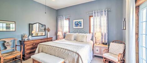 A bedroom with a large bed, a wooden chair, a nightstand, a dresser, and a ceiling fan.