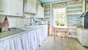 Une cuisine avec des meubles blancs, un évier en acier inoxydable, un four à micro-ondes et une table en bois.