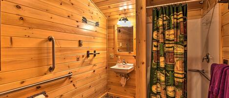 Ein Badezimmer aus Holz mit Waschbecken, Spiegel und einer Duschvorhang mit Etiketten von Flaschen.
