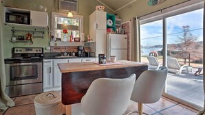 Una cocina con una isla de madera, sillas blancas y vistas al exterior.