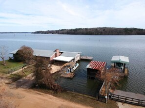 A lakeside property with a dock, a covered boat house, and a building with a metal roof. - Lakeside Pleasure Island Cabin w/ Deck & Gas Grill (Farmerville)