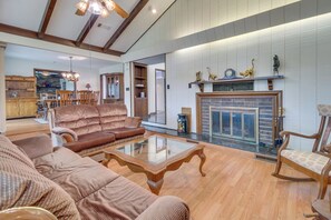 A spacious living room with a fireplace, wooden furniture, and a kitchen area in the background. - Gassville Home 3 Mi to White River & Trout Fishing (Gassville)