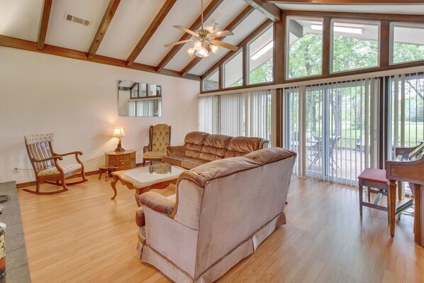 A spacious living room with a large sofa, a wooden coffee table, and a rocking chair. There is a piano and a mirror on the wall. - Gassville Home 3 Mi to White River & Trout Fishing (Gassville)