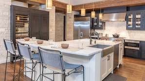 Una cocina moderna con una isla grande, armarios oscuros y un protector contra salpicaduras de piedra.