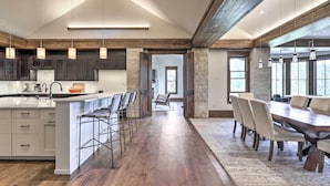 Una cocina amplia con una isla grande, suelo de madera oscura y un comedor con una mesa larga y sillas.