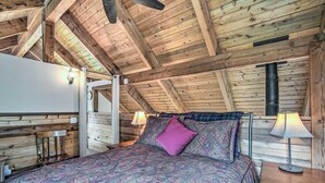 A cozy bedroom with a wooden ceiling, a bed with patterned bedding, two bedside lamps, and a nightstand with a drawer. - Peace in the Pines: Cle Elum Cabin w/ Trail! (Cle Elum)