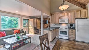 A spacious kitchen with wooden cabinets, a dining area with a table and chairs, and a large window offering a view of the outdoors. - Peace in the Pines: Cle Elum Cabin w/ Trail! (Cle Elum)