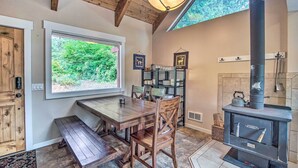 A cozy dining area with a wooden table and chairs, a built-in bookshelf, and a wood-burning stove. - Peace in the Pines: Cle Elum Cabin w/ Trail! (Cle Elum)