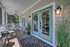 A covered porch with white wicker furniture, a blue door with wreaths, and hanging lanterns. - Bright & Airy Home: Chef's Kitchen & Pro Decor! (Michigan City)