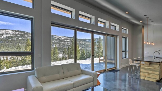 A modern living room with a large window, a sofa, and a glass coffee table. - Winters Gold in Alma: Big Views, 15 Mi to Breck (Alma)