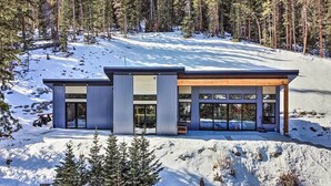 A modern, two-story cabin with large glass windows and a wooden deck, surrounded by a snowy forest. - Winters Gold in Alma: Big Views, 15 Mi to Breck (Alma)